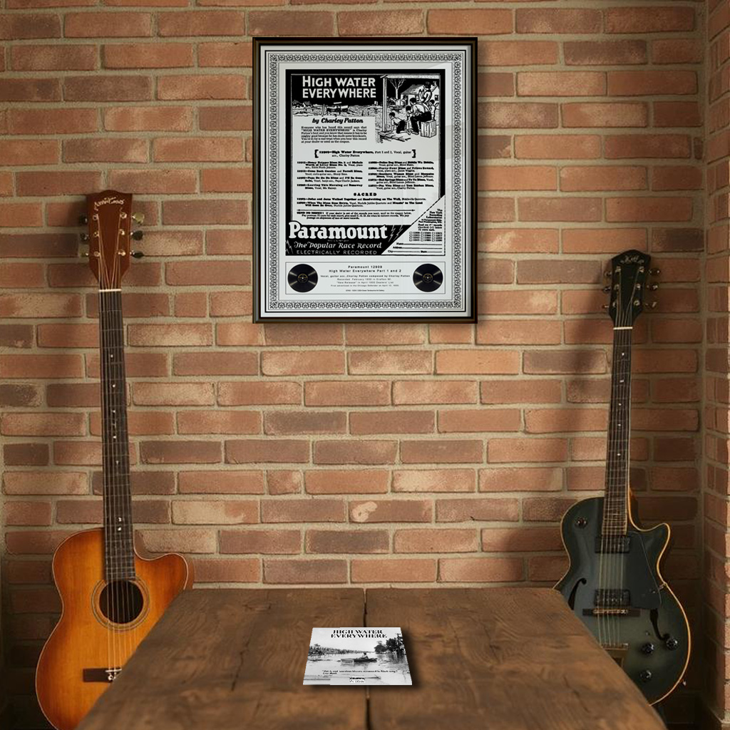 Charley Patton "High Water Everywhere" print in a black frame on a brick wall with two guitars leaning against it, and the "High Water Everywhere" CD displayed on a dark wood table.