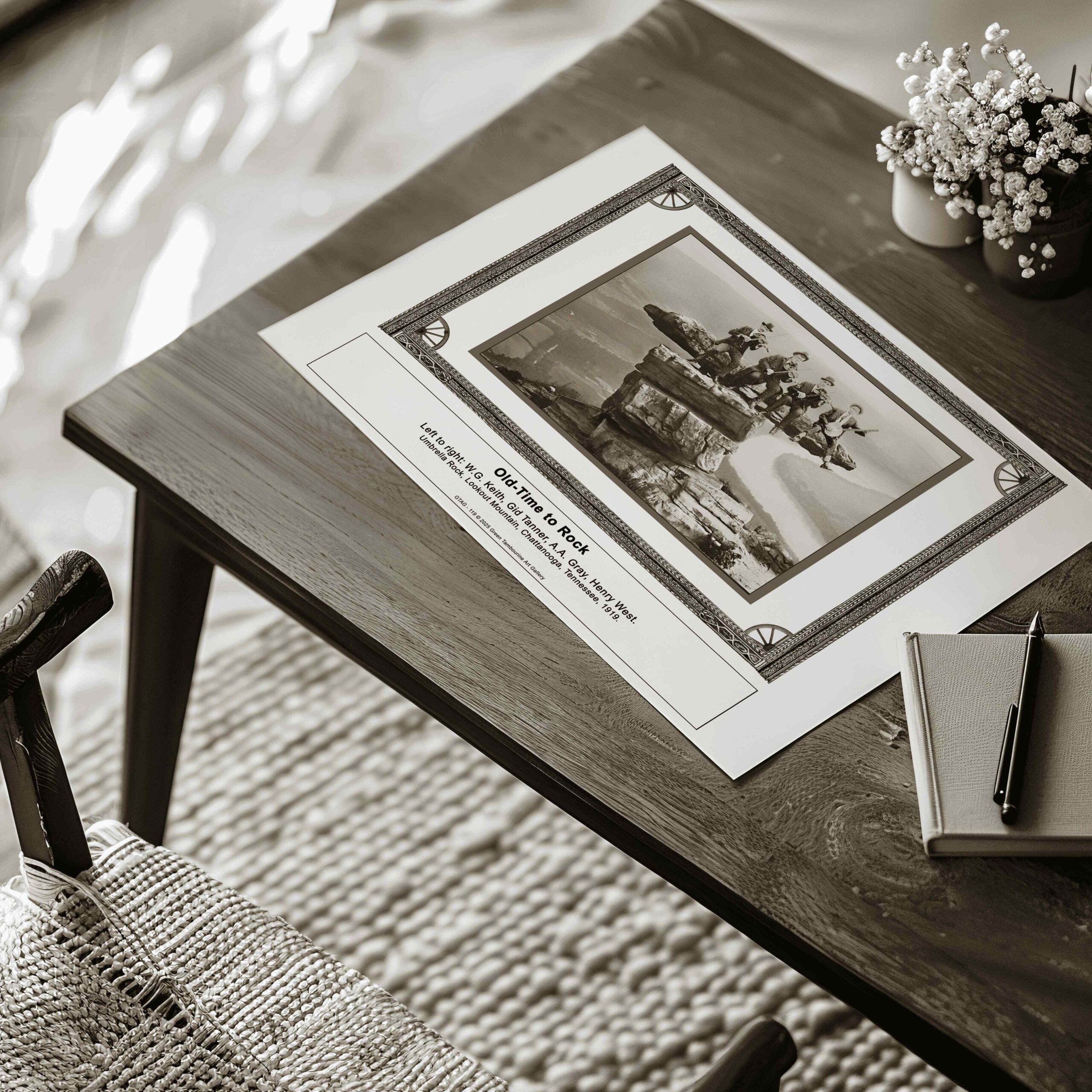 "An A5 fine art print (possibly appearing larger than A5) of Old Time Musicians – WG. Keith, Gid Tanner, AA Gray, Henry West – 1919, Lookout Mountain Print (SKU: GTAG-119) displayed on a wooden table. The artwork, unframed, is placed near a notebook, pen, and a decorative plant, giving a rustic and cozy aesthetic."
